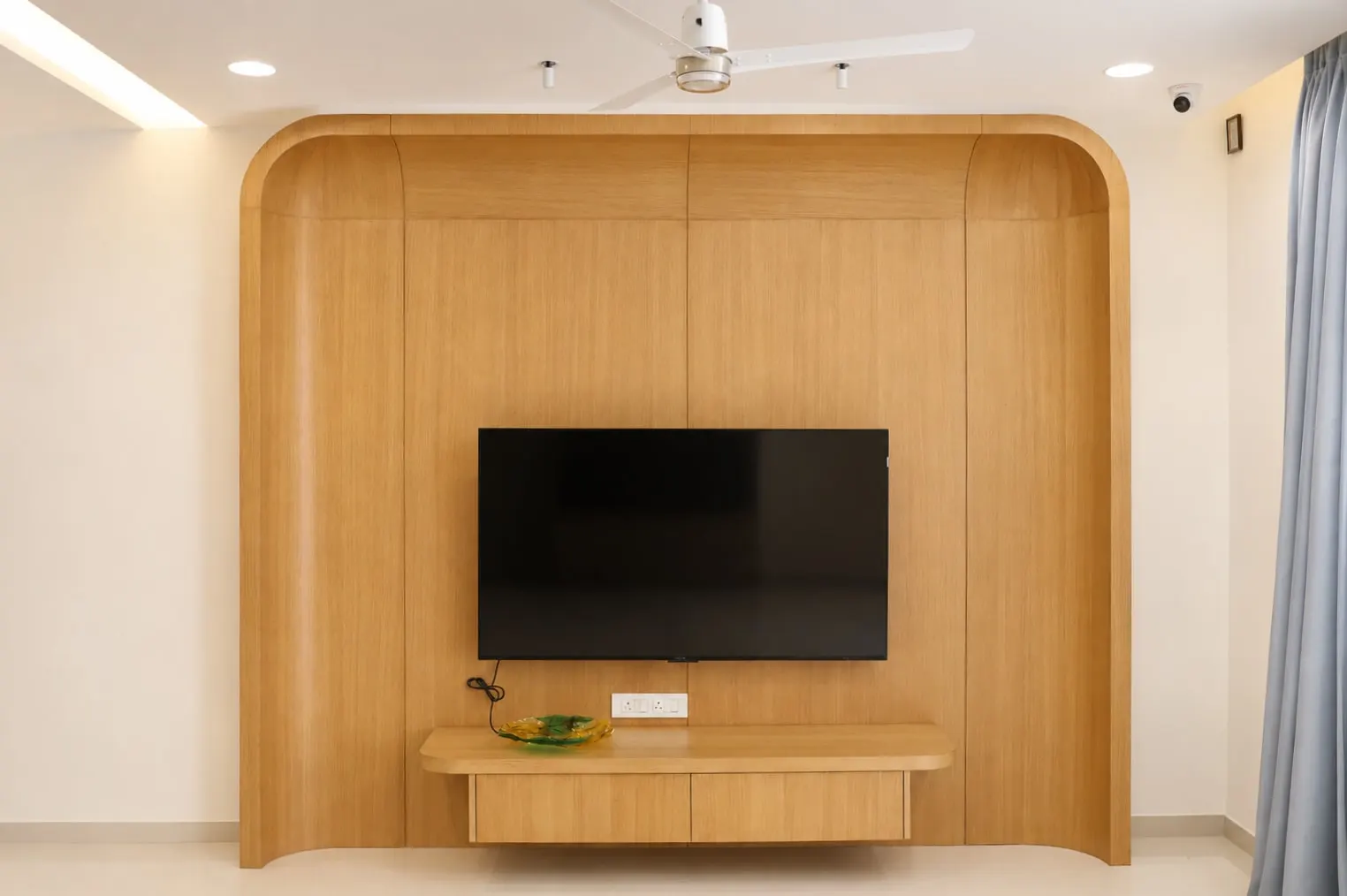 Curved walnut TV wall in a Hiranandani OMR home by Crafted Haven